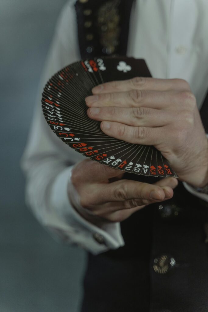 An illusionist elegantly displaying a fan of black playing cards during a magic performance.